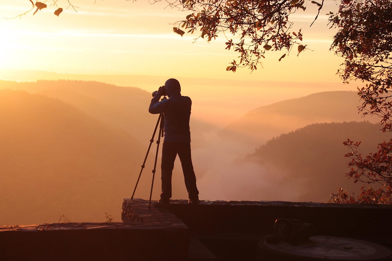 “Photographer taking a picture of the sunset with camera”
